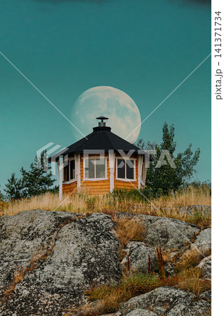 Small Finnish Wooden Cabin on a Rocky Hill with a Full Moon. 141371734