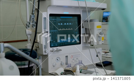 Modern medical ventilator with digital monitoring screen, breathing tubes, gauges, and control panel inside hospital intensive care room with soft clinical lighting and blurred equipment nearby Modern medical ventilator with digital monitoring screen, breathing tubes, gauges, and control panel inside hospital intensive care room with soft clinical lighting and blurred equipment nearby 141371805