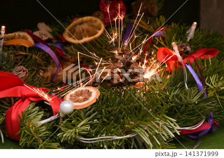 Dangerous Christmas wreath ignition from a sparkler with flying sparks Dangerous Christmas wreath ignition from a sparkler with flying sparks 141371999