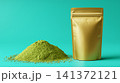 A presentation-ready mockup of a metallic gold pouch, featuring a small heap of green powder scattered nearby 141372121