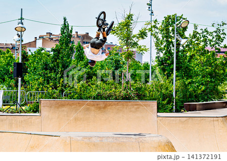 A young man practicing BMX and performing tricks at the skatepark A young man practicing BMX and performing tricks at the skatepark 141372191