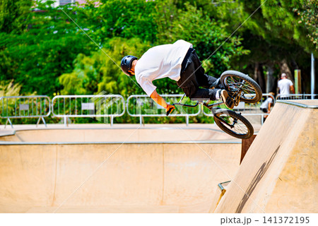 A young man practicing BMX and performing tricks at the skatepark A young man practicing BMX and performing tricks at the skatepark 141372195