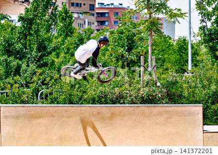 A young man practicing BMX and performing tricks at the skatepark 141372201