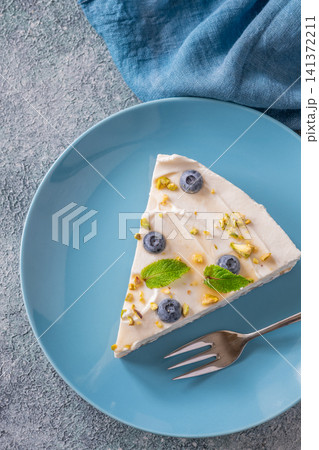 Creamy Mascarpone Cheesecake Slice Served With Blueberries Pistachios Maple Syrup And Mint Leaves Creamy Mascarpone Cheesecake Slice Served With Blueberries Pistachios Maple Syrup And Mint Leaves 141372211