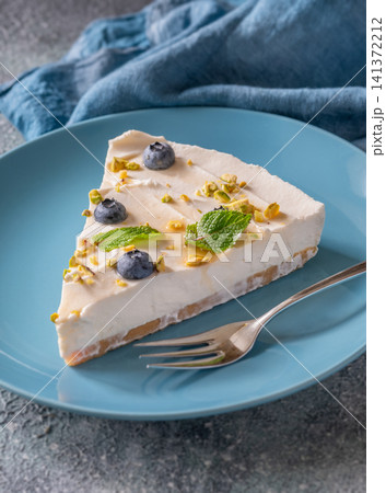 Creamy Mascarpone Cheesecake Slice Served With Blueberries Pistachios Maple Syrup And Mint Leaves Creamy Mascarpone Cheesecake Slice Served With Blueberries Pistachios Maple Syrup And Mint Leaves 141372212