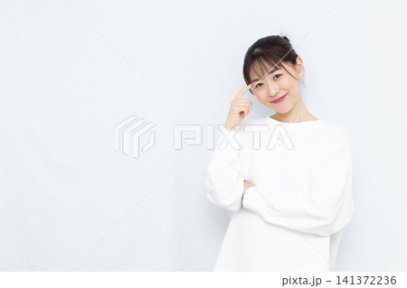 笑顔で頭を抱えて考えている女性 笑顔で頭を抱えて考えている女性 141372236