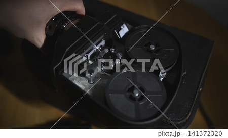 Hand holding open vintage tape recorder mechanism on wooden surface Hand holding open vintage tape recorder mechanism on wooden surface 141372320