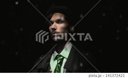 Serious man in dark hat with falling snow against black background Serious man in dark hat with falling snow against black background 141372421