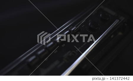 Detailed Shot Capturing Hand Adjusting Volume Knob On Black Audio Device With Moody Lighting. Media Detailed Shot Capturing Hand Adjusting Volume Knob On Black Audio Device With Moody Lighting. Media 141372442