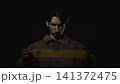 Serious man holding a yellow measuring strip in dark studio 141372475