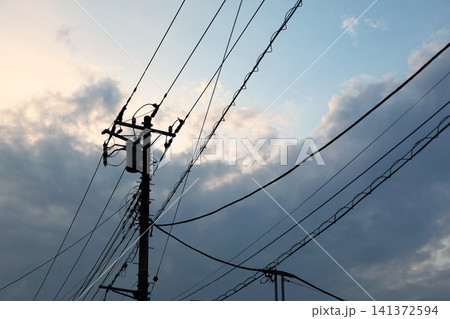 夕暮れ時の空に広がる電信柱と電線のシルエット 住宅街の夕景 夕暮れ時の空に広がる電信柱と電線のシルエット 住宅街の夕景 141372594