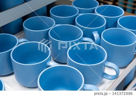 Blue cups and mugs in crockery shop, ceramic dishware, tableware stack in store Blue cups and mugs in crockery shop, ceramic dishware, tableware stack in store 141372886