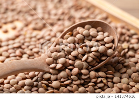 Close-up of raw green lentils in a wooden spoon, high protein plant-based food and meat alternative 141374616