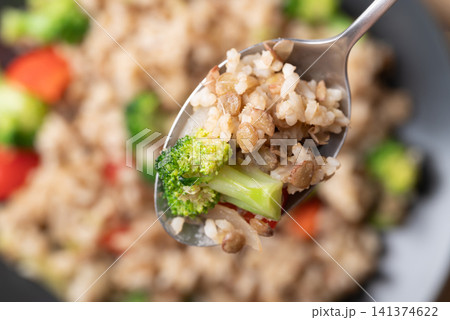 Close-up of lentil fried rice with broccoli and bell peppers in a spoon ready to eat Close-up of lentil fried rice with broccoli and bell peppers in a spoon ready to eat 141374622