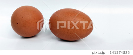 A close-up photo of two brown chicken eggs against a white background. A close-up photo of two brown chicken eggs against a white background. 141374826