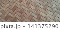 A close-up photo of a handmade bamboo weave texture with a diagonal herringbone pattern. 141375290