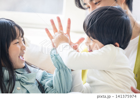 リビングで父親の手とハイタッチをして遊ぶ笑顔の子供たち 141375974