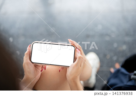 holding landscape smartphone mockup over her lap. 141376938
