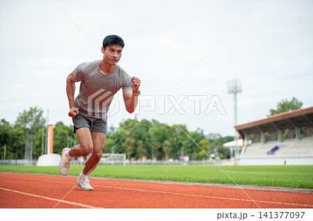 Full body of asian athletic man start running on track during a training session in sports stadium. Full body of asian athletic man start running on track during a training session in sports stadium. 141377097