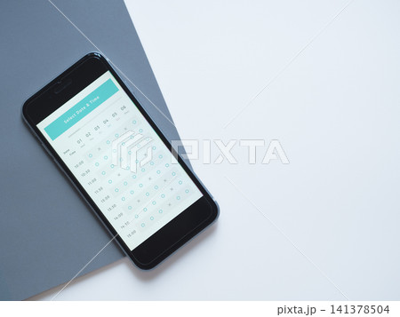 スマホに表示されたオンライン予約アプリの俯瞰写真 (画面はオリジナルイメージ) スマホに表示されたオンライン予約アプリの俯瞰写真 (画面はオリジナルイメージ) 141378504