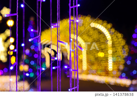 Purple LED light curtain in foreground with golden yellow tunnel bokeh background. Winter illumination festival night scene decoration 141378638