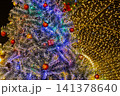 Beautiful decorated christmas tree closeup with red balls ornaments and yellow bokeh lights tunnel background at night winter holiday festival 141378640