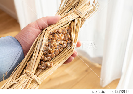 稲わらに包まれた発酵食品の納豆（ワラツト）を持つ男性 141378915