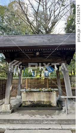 Traditional stone purification basin beneath a wooden pavilion 141382674