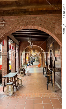 Long red brick arcade with repeating arches and lanterns 141383043