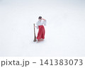 Miniature Shinto shrine maiden holds a sweeping broom. 141383073