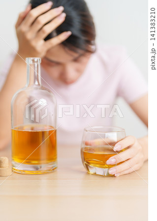Stressed woman drinking whisky alone with problem. Exhausted drunk man looking stressed and sleepy. Alcohol addiction, Alcoholism, emotional distress and mental health concept 141383210