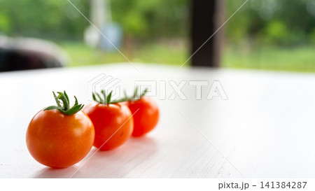 Fresh cherry tomatoes lined on white tabletop with soft garden background, bright natural daylight, minimal food composition, shallow depth of field, healthy organic produce, summer freshness, clean Fresh cherry tomatoes lined on white tabletop with soft garden background, bright natural daylight, minimal food composition, shallow depth of field, healthy organic produce, summer freshness, clean 141384287