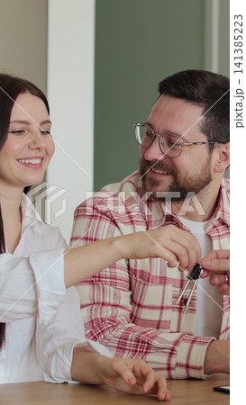 Vertical video Young family signing agreement with housing agent buying apartment getting keys. Couple moving to new apartment. Real estate concept. Vertical video Young family signing agreement with housing agent buying apartment getting keys. Couple moving to new apartment. Real estate concept. 141385223