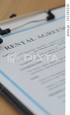 Vertical video Close-up view of a rental agreement document with key, and a pen placed on top. Property rental, leasing contracts, real estate. Vertical video Close-up view of a rental agreement document with key, and a pen placed on top. Property rental, leasing contracts, real estate. 141385230