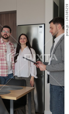 Vertical video Real estate agent man shows modern house to a young couple. Young couple client rent investment. Vertical video Real estate agent man shows modern house to a young couple. Young couple client rent investment. 141385259
