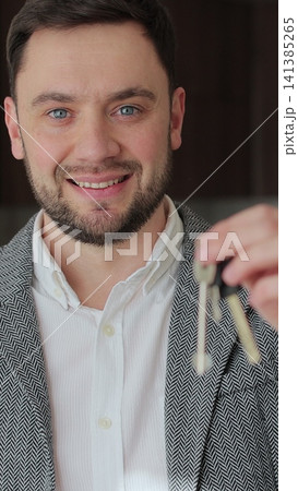 Vertical video Portrait of a happy man real estate agent holding the keys to new apartment. Satisfied new apartment owners in the background. Real estate. Vertical video Portrait of a happy man real estate agent holding the keys to new apartment. Satisfied new apartment owners in the background. Real estate. 141385265