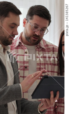 Vertical video Male real estate agent showing young couple apartment plan using electronic tablet. Home buying concept. Vertical video Male real estate agent showing young couple apartment plan using electronic tablet. Home buying concept. 141385267