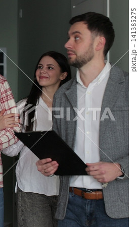 Vertical video Young couple with real-estate agent visiting apartment for sale or for rent. Loving people buying an apartment. Real estate concept. 141385275