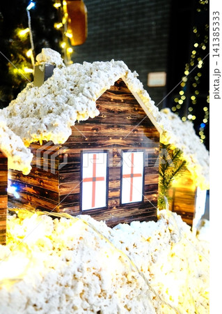 Miniature wooden house winter scene with festive lights Miniature wooden house winter scene with festive lights 141385333