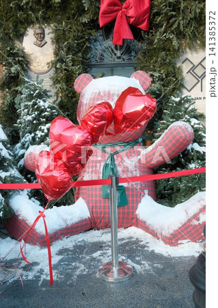 Giant plaid teddy bear with red heart balloons in winter Giant plaid teddy bear with red heart balloons in winter 141385372