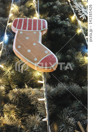 Dotted, striped gingerbread stocking ornament on a green lit tree. Dotted, striped gingerbread stocking ornament on a green lit tree. 141385426
