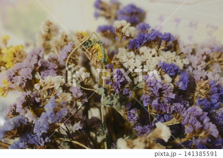 Bouquet of dried statice flowers in purple, yellow and white colors. Aesthetic natural decor for eco-friendly interior styling 141385591