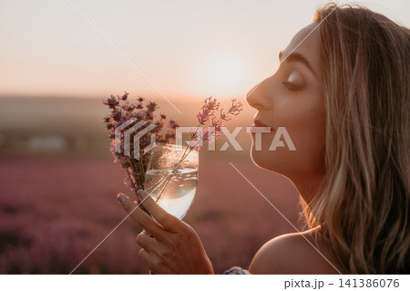 Woman lavender sunset enjoying peaceful moment in floral field holding glass of water with flowers at golden hour Woman lavender sunset enjoying peaceful moment in floral field holding glass of water with flowers at golden hour 141386076
