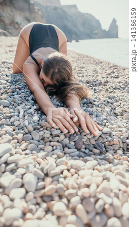 Woman yoga beach stretching in childs pose on pebbles by the sea for relaxation and summer wellness Woman yoga beach stretching in childs pose on pebbles by the sea for relaxation and summer wellness 141386159