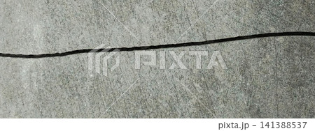 A horizontal crack splits the smooth, gray concrete surface. A horizontal crack splits the smooth, gray concrete surface. 141388537