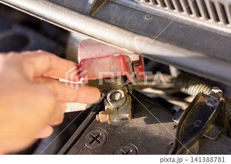Hand holding battery terminals to inspect connection and ensure stable electrical performance safely. 141388781
