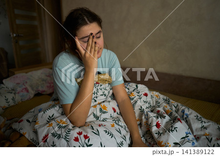 Teen girl waking up in bed rubbing eyes 141389122