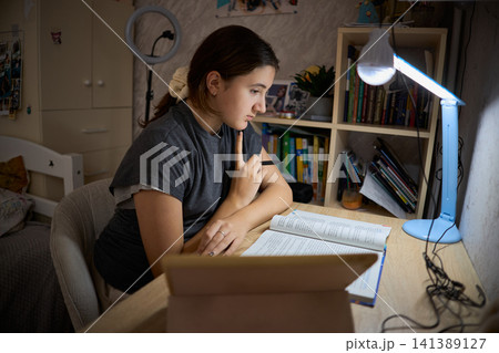 Teen girl studying by battery lamp during blackout 141389127