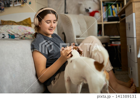 Teen girl petting Jack Russell in bedroom 141389131