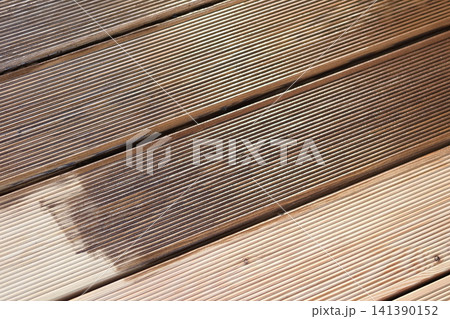 Brown oil for protection of wood by staining. Painting a larch for protecting and pests. Woodworker applying finish to terrace deck board. Repairman varnishing with brush wooden plank floor surface. 141390152